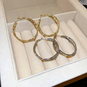 Minimalist twisted hoop earrings in gold and silver finish for a modern geometric look