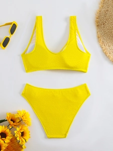 Flat lay of yellow textured bikini with sunflower and summer holiday accessories