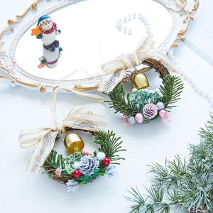 Mini Christmas wreath decorations with green, pink, and red berries on a wooden tray