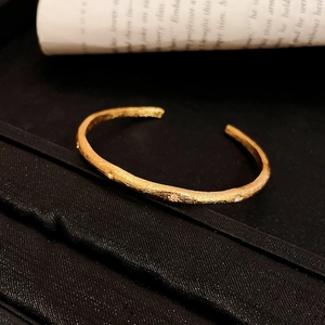 Detail of matte gold cuff bracelet featuring hammered texture and inlaid cubic zirconia