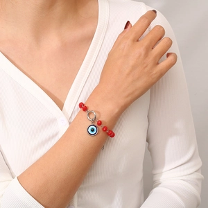 Detail of red beaded bracelet with blue evil eye charm worn on a model's wrist