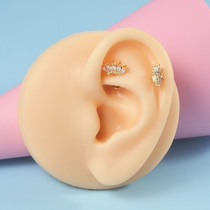 Detail of gold crown and flower labret studs with zircons on a silicone ear model