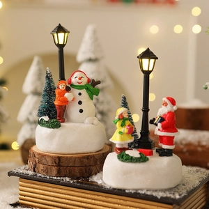 Dettaglio di miniature natalizie in resina con Babbo Natale su base innevata
