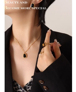 Close-up of elegant gold jewelry set with black opal stones on a fashion model