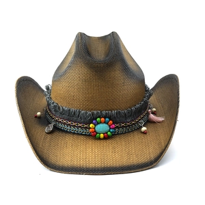 Détail d'un chapeau de cowboy en paille avec perles ethniques, pierre turquoise et franges