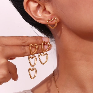 Detail of 18K gold-plated stainless steel hollow heart earrings worn on model's ear