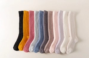 Flat lay of twelve assorted colorful coral fleece knee high socks in a neat arrangement
