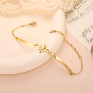 Detailed shot of golden stainless steel bracelet with infinity cross charm on a tray