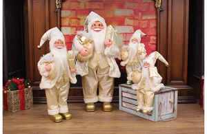 Detail of four beige and gold Santa Claus figurines standing by a cozy indoor fireplace