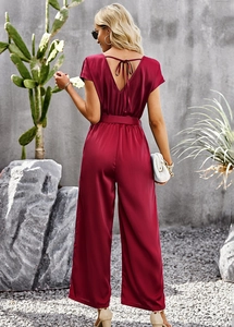 Detail of wine red satin jumpsuit showing back V-neck with tie-knot and wide leg design