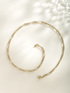 Detailed view of golden paperclip and link chain necklace with lobster clasp closure