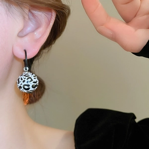 Gros plan d'un mannequin portant des boucles d'oreilles léopard avec perles en bois rétro