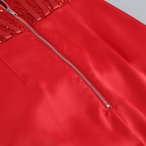Détail de robe rouge à paillettes montrant la fermeture éclair et le tissu soyeux