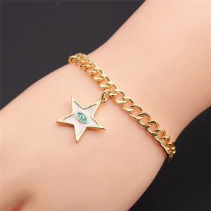 Macro shot of gold star charm bracelet featuring blue evil eye center on model wrist