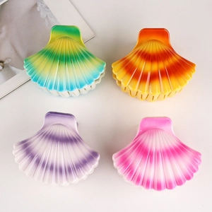Macro shot of four colorful gradient shell hair clips in green, orange, purple and pink
