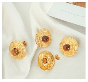Detail showing vintage gold spiral earrings with tiger eye stone on white silk