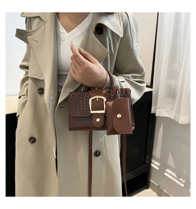 Close-up of brown croc-effect handbag with gold buckle and matching mini coin purse pouch