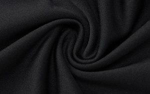 Macro shot of high-density black knit fabric showing texture and soft drape detail