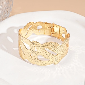 Detail of gold floral leaf textured cuff bracelet with intricate hollow cut-out patterns