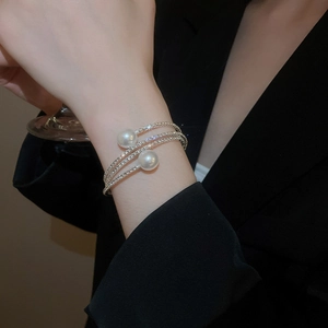 Detail of multi-layer silver wrap bracelet with shimmering rhinestones and large white pearls