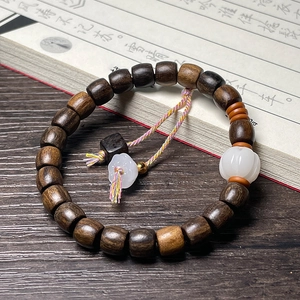 Macro detail of wood prayer beads with white jade pumpkin pendant and silk tassel