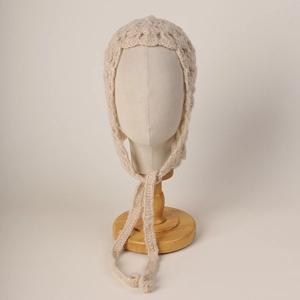 Detailed knit texture of beige mohair hooded hat with elegant lace-up ties