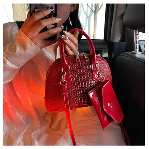 Detail of red crocodile pattern shell bag with small pouch in a car interior setting