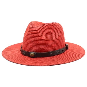 Détail d'un chapeau fedora rouge avec bande en cuir marron et boucle en métal décorative