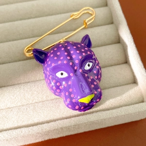 Vue détaillée d'une broche tête de léopard violette à pois roses sur un plateau en velours