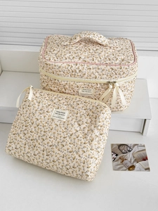 Détail de la trousse de toilette matelassée à fleurs avec fermeture éclair et poignée