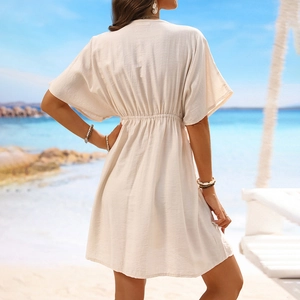 Rear view of a beige short sleeve beach cover-up dress with elastic waist and lace detail