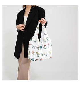 Detail of white canvas tote bag featuring vibrant floral prints and sturdy carry handles