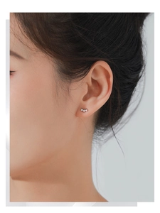 Close-up of a delicate S925 sterling silver candy-shaped stud earring on a model ear