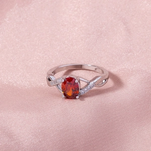 Detailed macro view of an oval red gemstone ring on elegant pink silk fabric background