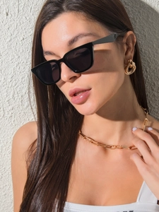 Artistic lighting on black cat-eye sunglasses and gold twisted hoop earrings