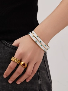 Detail of model wearing evil eye enamel bracelets and heart shaped gold rings