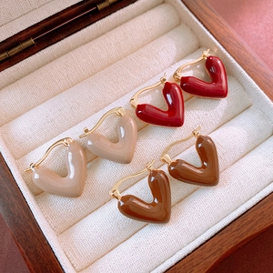 Detail view of heart-shaped oil-dripping earrings in red, beige and brown finishes
