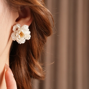 Detail of French vintage white camellia stud earrings crafted with delicate seed beads