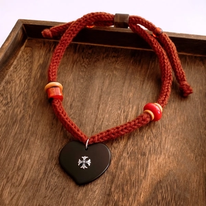 Detail of hand-woven cord necklace with black heart pendant and silver cross icon
