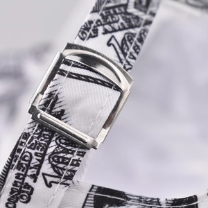 Detail of adjustable metal buckle and currency print on the baseball cap strap