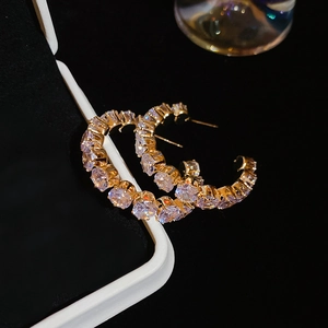 Macro detail of gold hoop earrings with sparkling rhinestones on elegant jewelry box