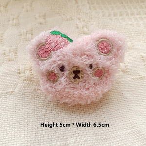 Detail of pink plush bear pin with strawberry embroidery, dimensions 5cm by 6.5cm