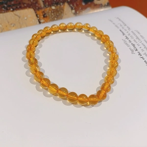 Macro shot of 6-8mm yellow citrine beads with natural textures on a vintage book