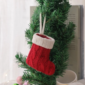 Mini red knitted Christmas stocking decoration hanging on a tree with white cuff