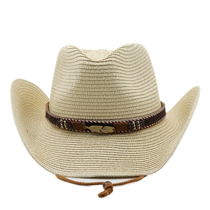 Dettaglio di un cappello di paglia cowboy con fascia di perline e ciondolo a piuma dorata