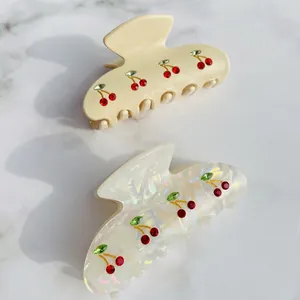 Pastel cream and pearl white acetate hair claws with sparkling rhinestone cherry pattern