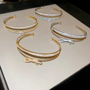 Macro detail of double-layer bow bracelets featuring zircon stones in gold and silver plating