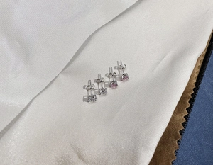Detailed macro view of four-prong 925 silver stud earrings with pink and white cubic zirconia