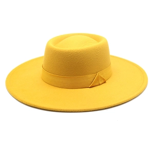 Detail of a bright yellow wide-brim boater hat with matching ribbon and wool felt texture