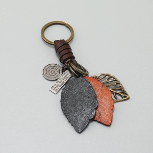 Detail of vintage bronze key ring with leather wrap and engraved metal leaf pendants